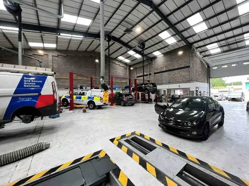 Inside the Hopfields workshop — vans and a police car in for work, with the alignment pit in the foreground